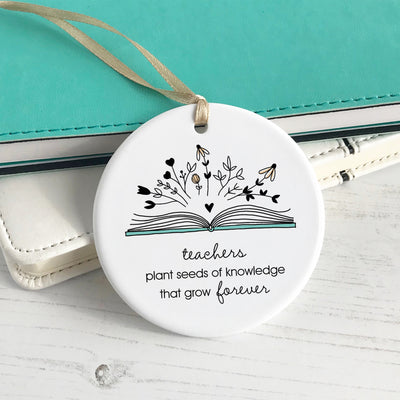 ceramic ornament with a book in bloom. Phrase reads "teachers plant seeds of knowledge that grow forever"